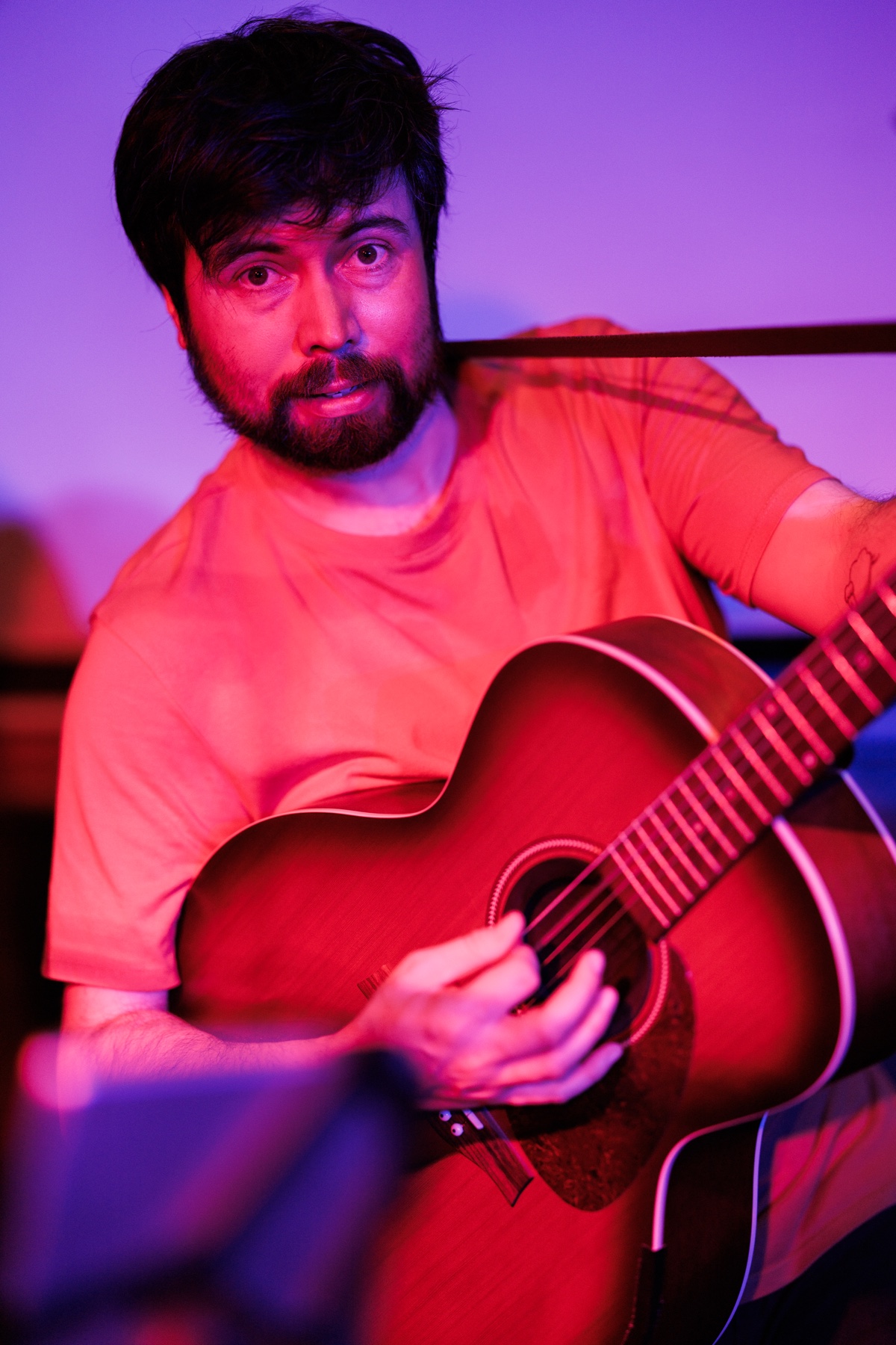 Guitariste en concert au Rambler sous les lumières violettes et rouges