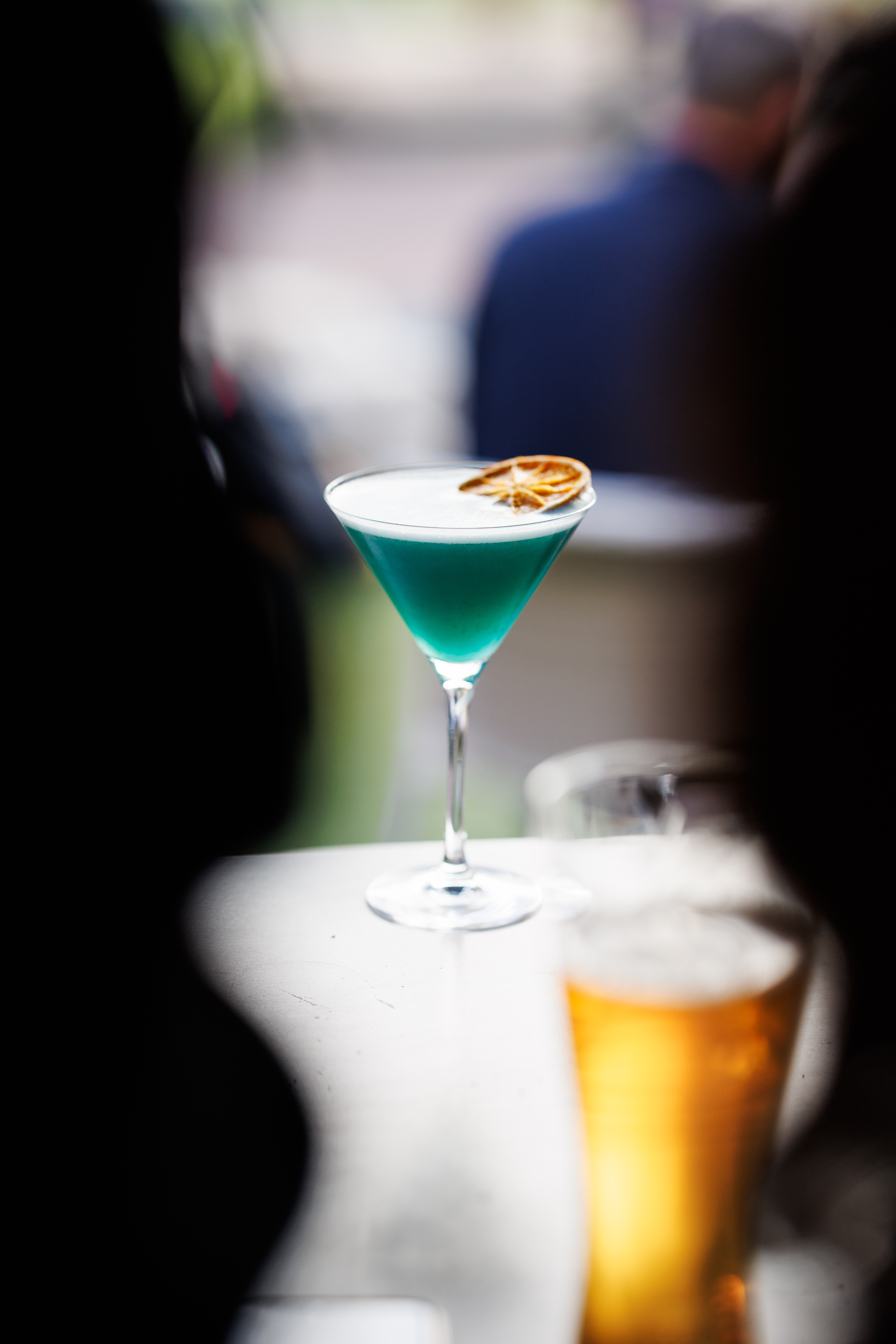 Cocktail bleu servi au Rambler avec une bière au premier plan